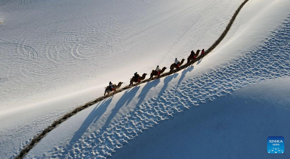 This aerial photo taken on Nov. 15, 2023 shows tourists enjoying snow scenery of the Mingsha Mountain and Crescent Spring scenic spot in Dunhuang, northwest China's Gansu Province.(Photo: Xinhua)
