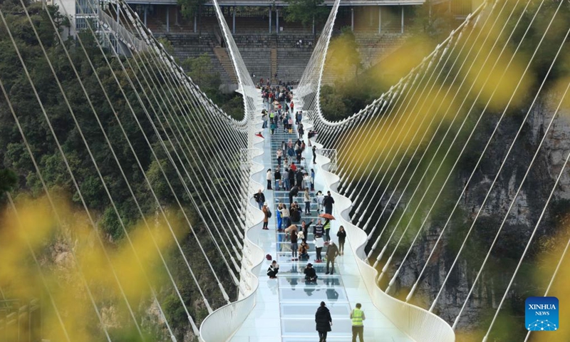 Tourists walk on a glass-bottomed bridge at Zhangjiajie Grand Canyon in central China's Hunan Province, Nov. 18, 2023. (Photo: Xinhua)