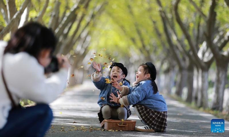 A woman takes photos of children playing with fallen leaves at a park in Jiangdu District of Yangzhou, east China's Jiangsu Province, Nov. 18, 2023. (Photo: Xinhua)