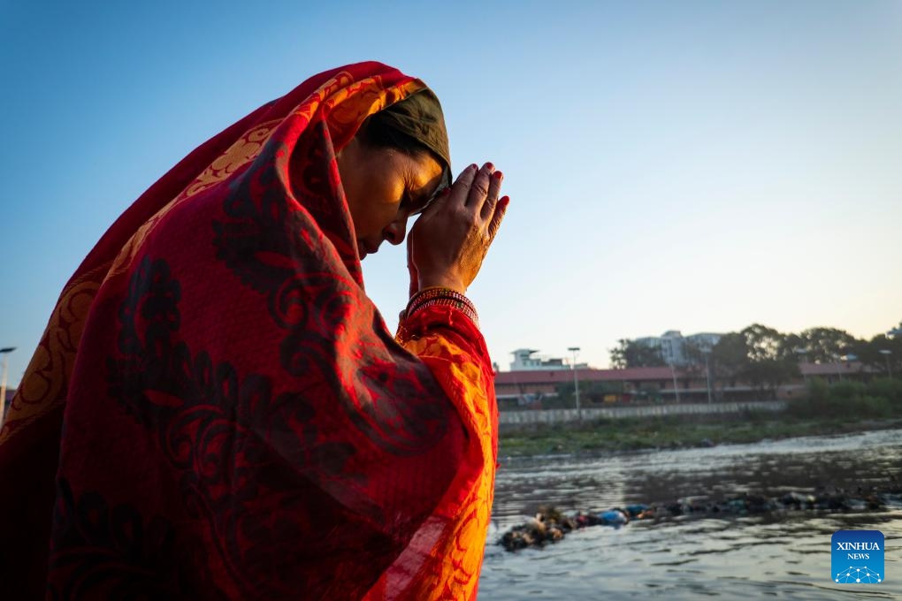 A woman worships the rising sun during the Chhath festival on the bank of the Bagmati River in Kathmandu, Nepal, Nov. 20, 2023. The Chhath festival is dedicated to the Sun with devotees making offerings to the setting and rising Sun(Photo: Xinhua)