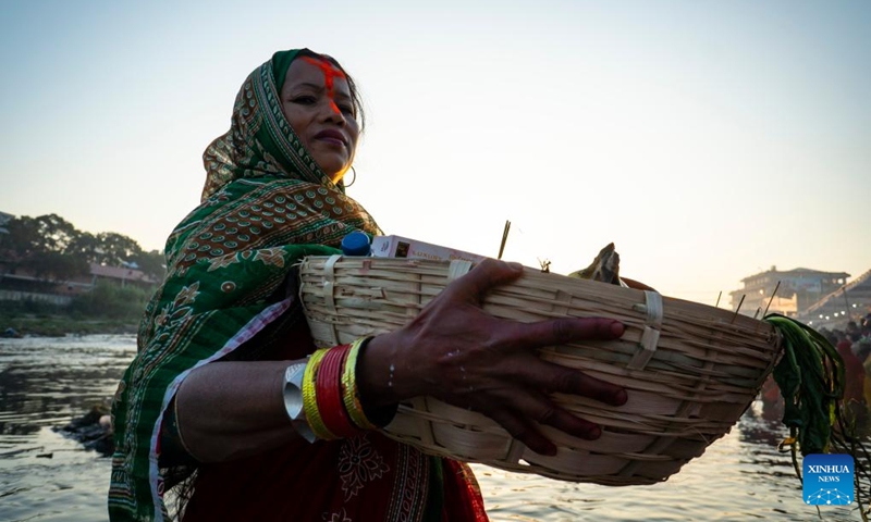 A woman worships the rising sun during the Chhath festival on the bank of the Bagmati River in Kathmandu, Nepal, Nov. 20, 2023. The Chhath festival is dedicated to the Sun with devotees making offerings to the setting and rising Sun(Photo: Xinhua)