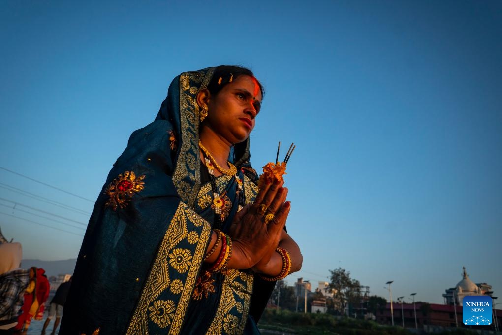 A woman worships the rising sun during the Chhath festival on the bank of the Bagmati River in Kathmandu, Nepal, Nov. 20, 2023. The Chhath festival is dedicated to the Sun with devotees making offerings to the setting and rising Sun(Photo: Xinhua)