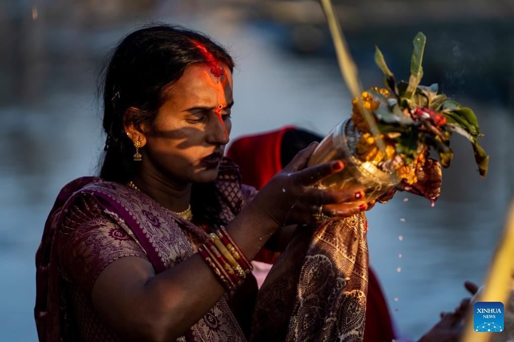 A woman worships the rising sun during the Chhath festival on the bank of the Bagmati River in Kathmandu, Nepal, Nov. 20, 2023. The Chhath festival is dedicated to the Sun with devotees making offerings to the setting and rising Sun(Photo: Xinhua)