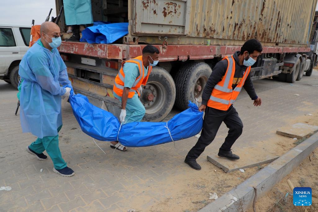 Palestinian workers transfer a body as they establish a mass grave for the victims inside and north of Gaza City, in the southern Gaza Strip city of Khan Younis, on Nov. 22, 2023. The Palestinian death toll in the Gaza Strip has risen to 14,532 since the outbreak of the Hamas-Israel conflict on Oct. 7, the Hamas-run government media office said Wednesday(Photo: Xinhua)