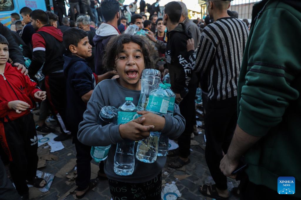 Palestinian people get drinking water from trucks loaded with food supplies in the southern Gaza Strip city of Khan Younis, on Nov. 21, 2023. The Palestinian death toll in the Gaza Strip has surpassed 14,000 since the current Israel-Hamas conflict broke out on Oct. 7, the Hamas-run government media office said Tuesday.(Photo: Xinhua)