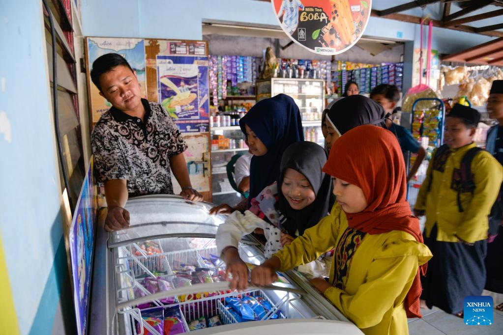 Children choose Aice ice cream products from a freezer at a store run by Andy Setiawan's family in Mojokerto, East Java, Indonesia, Sept. 14, 2023. Living in the tropics, the Indonesian people swelter through the scorching weather. Aice, a famous ice cream brand in the country, cools them down and brings joy.(Photo: Xinhua)