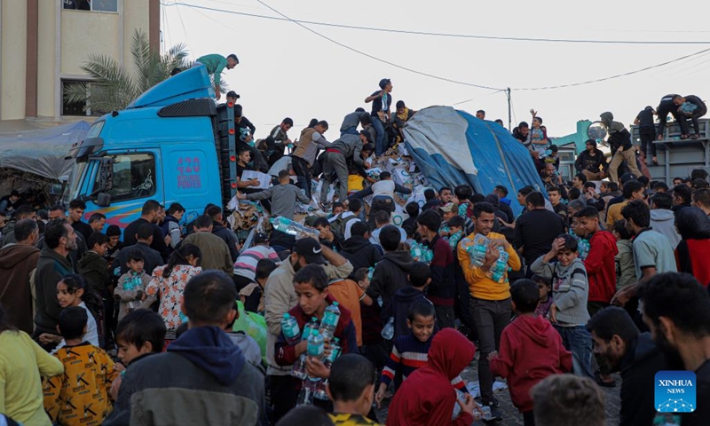 Palestinian people get drinking water from trucks loaded with food supplies in the southern Gaza Strip city of Khan Younis, on Nov. 21, 2023. The Palestinian death toll in the Gaza Strip has surpassed 14,000 since the current Israel-Hamas conflict broke out on Oct. 7, the Hamas-run government media office said Tuesday.(Photo: Xinhua)