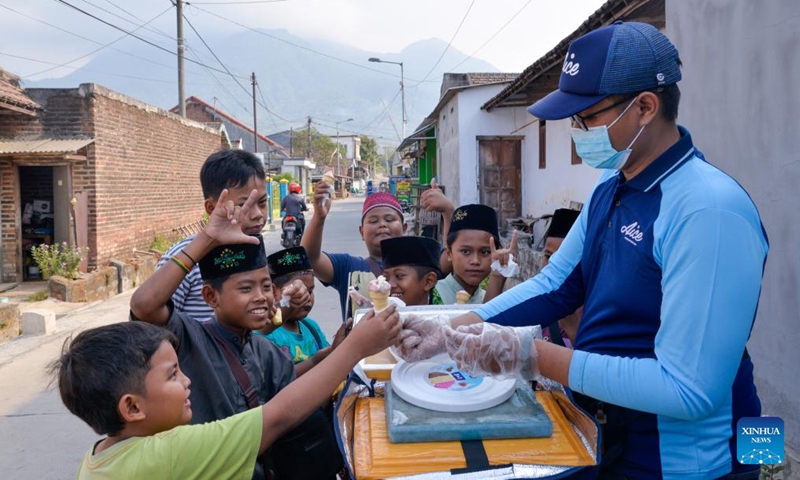 Children buy Aice ice cream from Yusuf Afat's Aice ice cream sales bicycle in Mojokerto, East Java, Indonesia, Sept. 14, 2023. Living in the tropics, the Indonesian people swelter through the scorching weather. Aice, a famous ice cream brand in the country, cools them down and brings joy.(Photo: Xinhua)