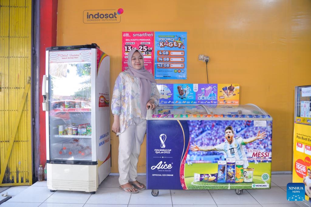 Yadi poses for photos with a freezer at her store in Mojokerto, East Java, Indonesia, Sept. 14, 2023. Living in the tropics, the Indonesian people swelter through the scorching weather. Aice, a famous ice cream brand in the country, cools them down and brings joy.(Photo: Xinhua)