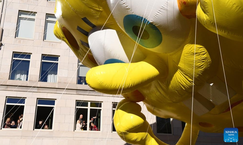 People watch the balloon of Spongebob Squarepants and Gary by windows during the 2023 Macy's Thanksgiving Day Parade in New York, the United States, on Nov. 23, 2023. (Photo: Xinhua)