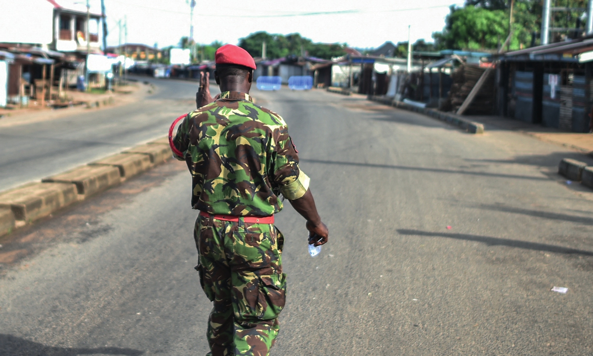 A soldier with the Sierra Leonean military police greets a man along an empty road in capital Freetown on November 26, 2023. The government declared a nationwide curfew after assailants attacked the armoury at the Wilberforce barracks in the early hours of November 26.Photo: AFP