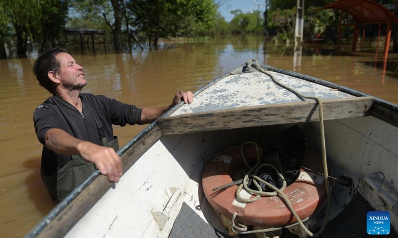 A resident pulls a boat on a flooded avenue in Canoas, Rio Grande do Sul, Brazil, Nov. 24, 2023. (Photo: Xinhua)