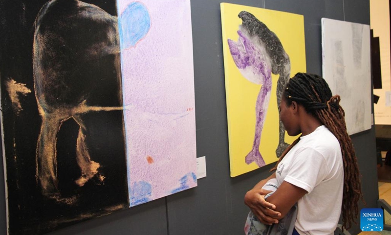 A visitor watches art works exhibited during the exhibition of works of young Chinese and Beninese artists at the Chinese Cultural Center in Cotonou, Benin, Nov. 25, 2023. An exhibition featuring works by 11 Beninese and Chinese artists opened here Saturday evening, aiming to celebrate booming cultural exchanges between the two countries' young artists. (Photo: Xinhua)