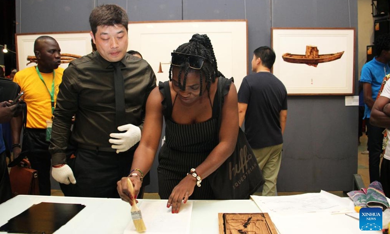A visitor learns under the guidance of Chinese artist Wang Guanzhou during the exhibition of works of young Chinese and Beninese artists at the Chinese Cultural Center in Cotonou, Benin, Nov. 25, 2023. An exhibition featuring works by 11 Beninese and Chinese artists opened here Saturday evening, aiming to celebrate booming cultural exchanges between the two countries' young artists. (Photo: Xinhua)