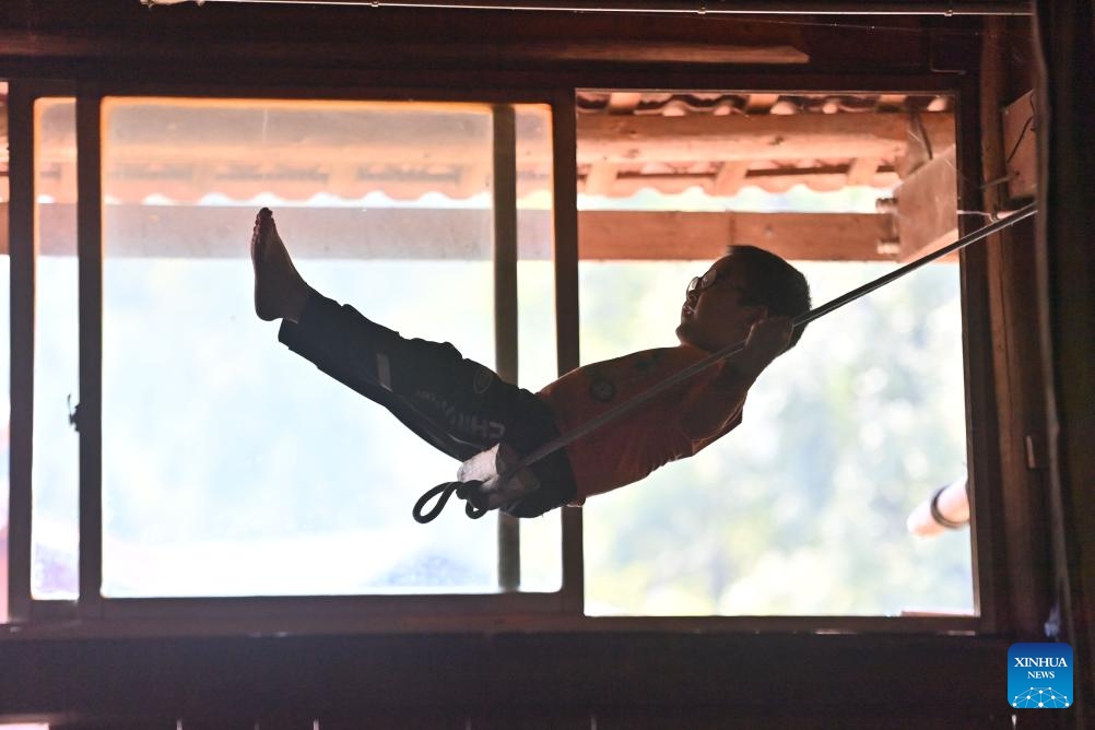 A boy plays on swing in a stilt building in Wuying Village on the border between south China's Guangxi Zhuang Autonomous Region and southwest China's Guizhou Province, Oct, 4, 2023. Wuying Village is a Miao ethnic group hamlet that nestles snugly in the towering mountains stretching across the border between Guangxi and Guizhou. Most villagers are still living in traditional wood stilt buildings. (Photo: Xinhua)