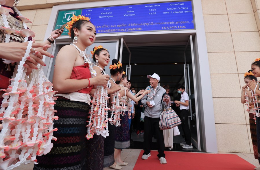 Lao staff members greet passengers taking the first cross-border passenger train from Kunming in southwest China's Yunnan Province to Lao capital Vientiane at the Boten Station of the China-laos Railway in Luang Namtha, Laos on April 13, 2023.(Photo: Xinhua)