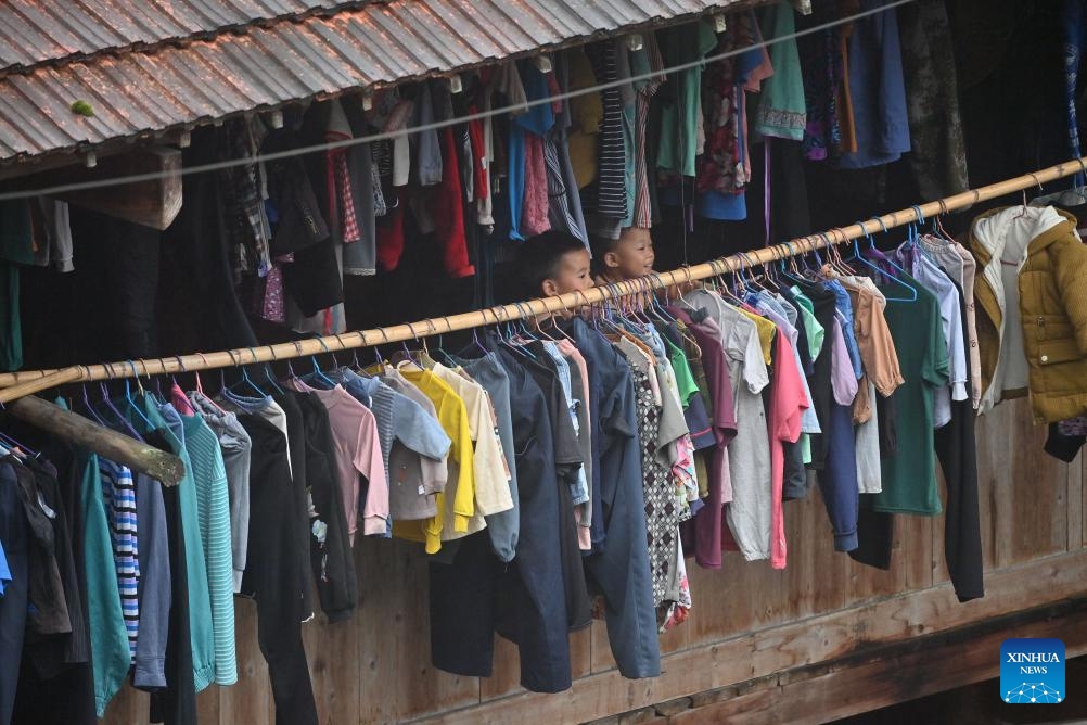 Two kids look out of the window of a stilt building in Wuying Village on the border between south China's Guangxi Zhuang Autonomous Region and southwest China's Guizhou Province, Oct, 14, 2023. Wuying Village is a Miao ethnic group hamlet that nestles snugly in the towering mountains stretching across the border between Guangxi and Guizhou. Most villagers are still living in traditional wood stilt buildings.(Photo: Xinhua)