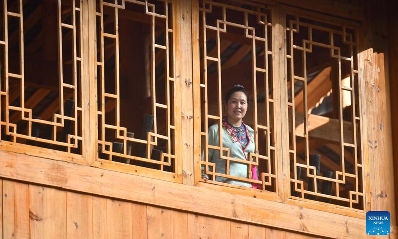 A woman looks out of the window of a stilt building in Wuying Village on the border between south China's Guangxi Zhuang Autonomous Region and southwest China's Guizhou Province, Oct, 4, 2023. Wuying Village is a Miao ethnic group hamlet that nestles snugly in the towering mountains stretching across the border between Guangxi and Guizhou. Most villagers are still living in traditional wood stilt buildings.(Photo: Xinhua)