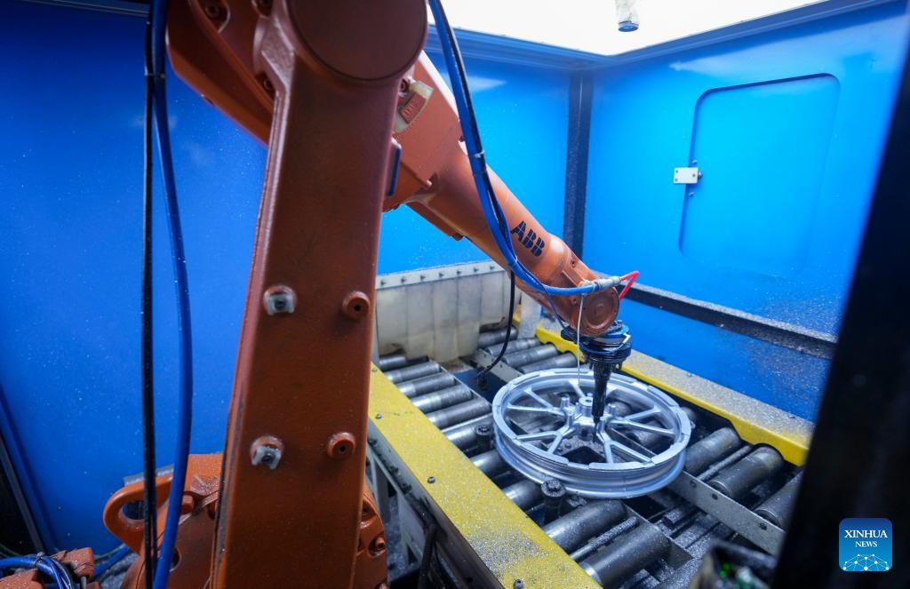 An industrial robot performs fine processing of a semi-finished wheel hub product at an automatic hub production line of a leading motorcycle wheel hub manufacturing enterprise in Dianjiang County of Chongqing, southwest China, Nov. 28, 2023. Chongqing is one of the important production and export bases of motorcycle parts in China. In recent years, Dianjiang County of Chongqing has guided local leading motorcycle wheel hub production enterprises to rely on scientific and technological innovations to promote industrial upgrading.(Photo: Xinhua)