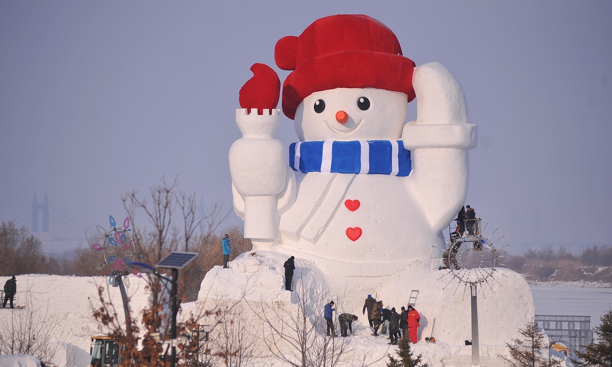 Workers make a giant snowman on the banks of the Songhua River in Harbin, Northeast China's Heilongjiang Province, on December 5, 2023. Wearing a red velvet hat and with a big carrot nose, the nearly 20-meter-tall snowman brings some warmth to the cold winter with its big smile. Photo: VCG