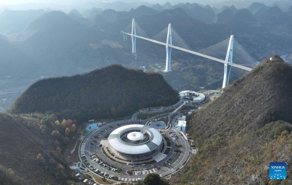 This aerial photo taken on Dec. 6, 2023 shows the Pingtang grand bridge and Sky Bridge sightseeing service area in Pingtang County, southwest China's Guizhou Province. Due to the large number of bridges, their types, and the complex technologies used in the construction of the bridges, Guizhou is known as the museum of world bridges. For years, the province has developed tourism drawing upon these bridges to boost economic growth.(Photo: Xinhua)