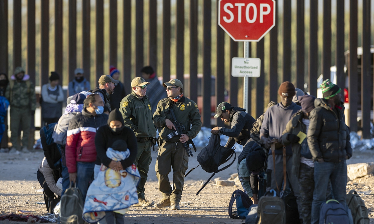 US border patrol agents supervise as immigrants await transport from the US-Mexico border on December 07, 2023 in Lukeville, Arizona. A surge of immigrants illegally passing through openings cut by smugglers in the border wall has overwhelmed US immigration authorities, causing them to shut down several international ports of entry so that officers can help process the new arrivals. Photo: VCG