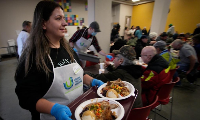 A volunteer serves food during the annual Christmas dinner at Union Gospel Mission (UGM) in Vancouver, British Columbia, Canada, on Dec. 9, 2023. (Photo: Xinhua)