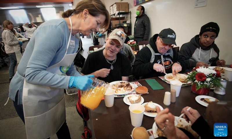 A volunteer serves drink during the annual Christmas dinner at Union Gospel Mission (UGM) in Vancouver, British Columbia, Canada, on Dec. 9, 2023. (Photo: Xinhua)