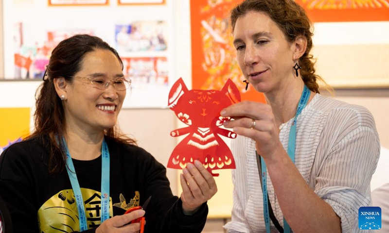 An Italian artist (R) learns about paper-cutting techniques from You Jinmei, an inheritor of intangible cultural heritage, during an intangible cultural heritage exhibition on the Maritime Silk Road in Quanzhou, southeast China's Fujian Province, Dec. 9, 2023. The city of Quanzhou is widely believed to be the starting point of the ancient Maritime Silk Road. (Photo: Xinhua)