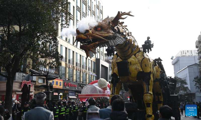 People watch as the mechanical device Horse Dragon Long Ma parades on a street in Gongshu District of Hangzhou, east China's Zhejiang Province, Dec. 16, 2023. (Xinhua/Huang Zongzhi)