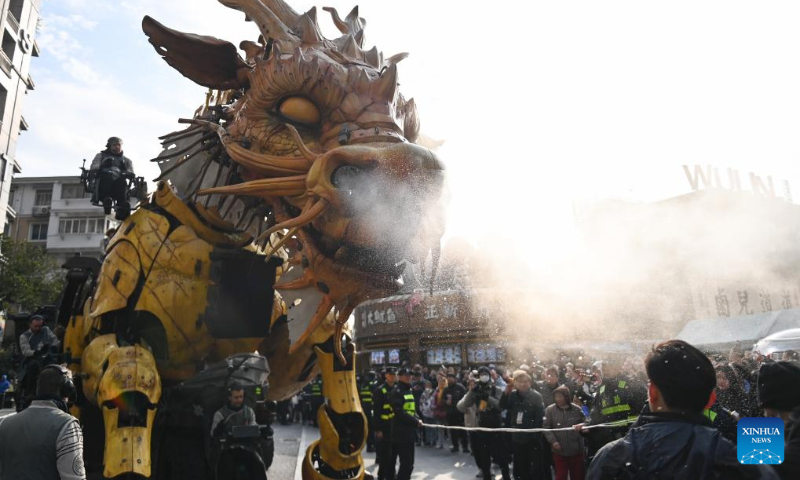 People watch as the mechanical device Horse Dragon Long Ma parades on a street in Gongshu District of Hangzhou, east China's Zhejiang Province, Dec. 16, 2023. (Xinhua/Huang Zongzhi)