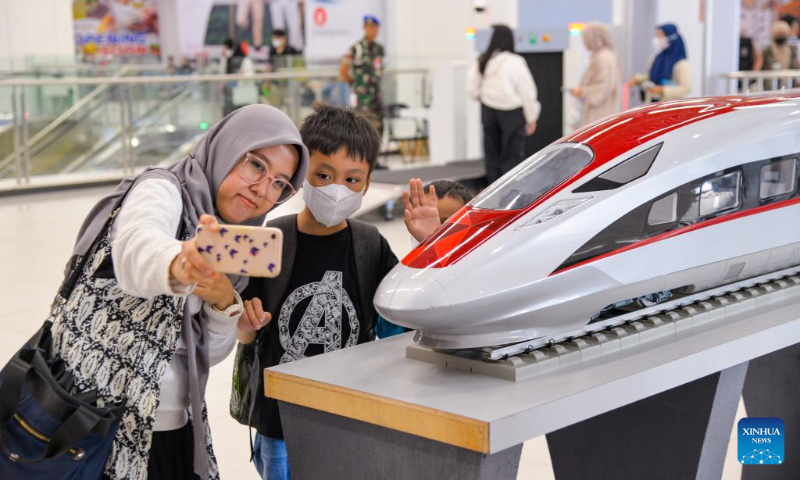 Passengers take a selfie with a model of a high-speed electrical multiple unit (EMU) train of the Jakarta-Bandung high-speed railway at Halim Station in Jakarta, Indonesia, Dec. 17, 2023. According to PT Kereta Cepat Indonesia-China (KCIC), a joint venture consortium between Indonesian and Chinese state-owned firms that constructs and runs the Jakarta-Bandung high-speed railway (HSR), the HSR has delivered more than 700,000 passengers since it was officially put into commercial operation on Oct. 17. (Xinhua/Xu Qin)