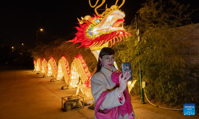 A visitor takes selfies at the Year of the Dragon Lantern Festival in Budapest Zoo in Budapest, Hungary, Dec. 16, 2023. (Photo by Attila Volgyi/Xinhua)