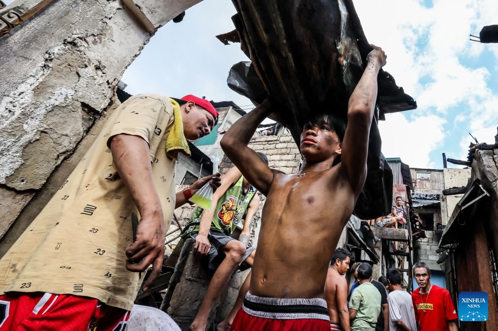 Residents collect reusable materials from their charred homes after a fire at a slum area in Manila, the Philippines on Dec. 12, 2023. The pre-dawn fire that erupted Tuesday left 240 families homeless, the Philippine Bureau of Fire Protection said.(Photo: Xinhua)