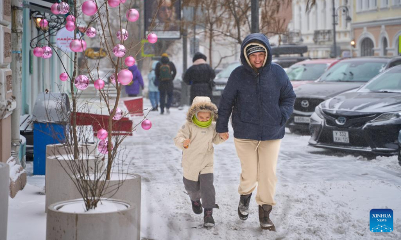 A mother and her child walk in the blizzard in Vladivostok, Russia, Dec. 16, 2023. (Photo by Guo Feizhou/Xinhua)