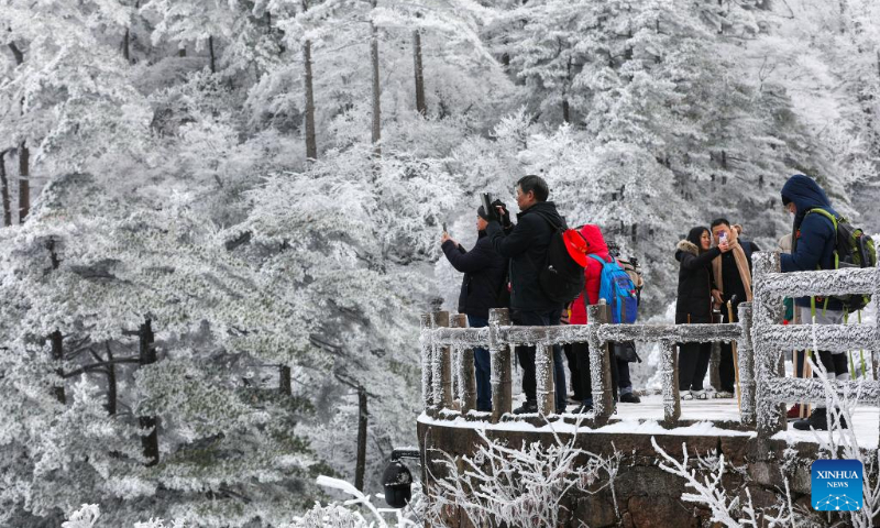 Tourists enjoy the snow scenery at the Huangshan Mountain scenic area in Huangshan City, east China's Anhui Province, Dec. 16, 2023. The scenic area witnessed the first snowfall in this winter recently. (Photo by Fan Chengzhu/Xinhua)