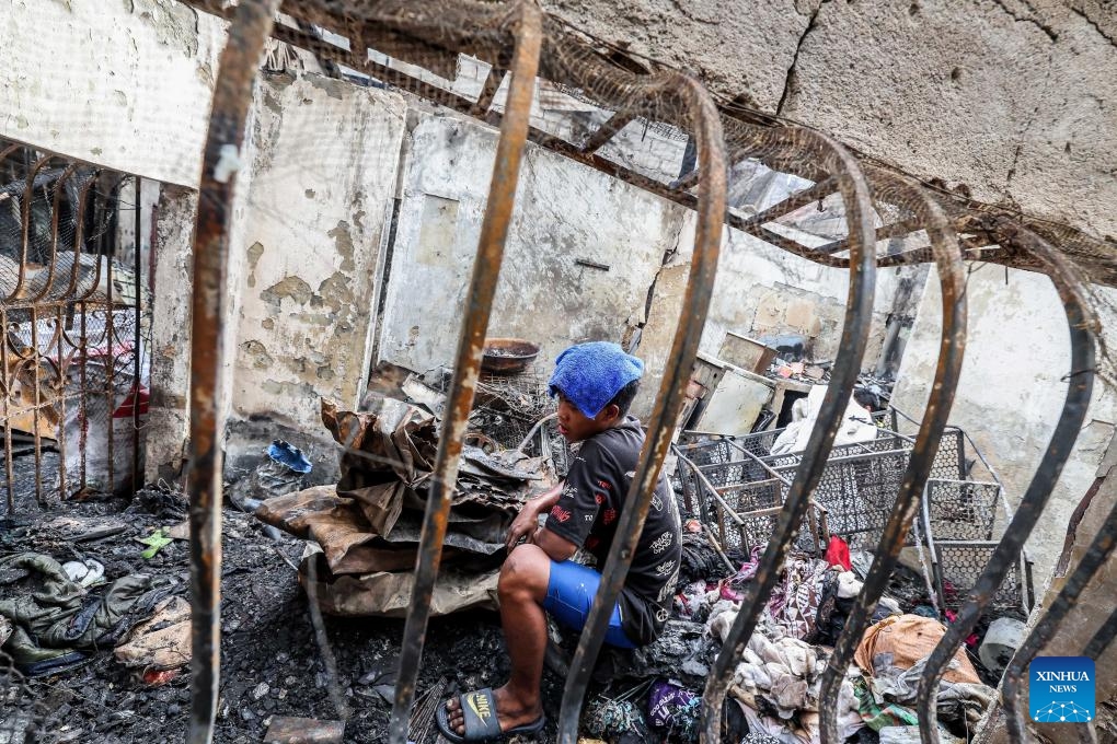 A resident looks for reusable materials from his charred home after a fire at a slum area in Manila, the Philippines on Dec. 12, 2023. The pre-dawn fire that erupted Tuesday left 240 families homeless, the Philippine Bureau of Fire Protection said.(Photo: Xinhua)