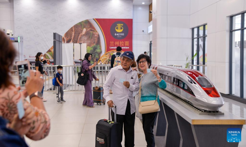 Passengers pose for photos with a model of a high-speed electrical multiple unit (EMU) train of the Jakarta-Bandung high-speed railway at Halim Station in Jakarta, Indonesia, Dec. 17, 2023. According to PT Kereta Cepat Indonesia-China (KCIC), a joint venture consortium between Indonesian and Chinese state-owned firms that constructs and runs the Jakarta-Bandung high-speed railway (HSR), the HSR has delivered more than 700,000 passengers since it was officially put into commercial operation on Oct. 17. (Xinhua/Xu Qin)