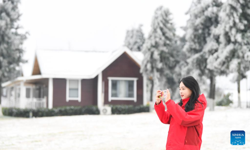 A visitor takes photos of snow scenery at the Chuanhegai scenic spot in Yongdong Town, Xiushan Tujia and Miao Autonomous County in Chongqing, southwest China, Dec. 16, 2023. (Xinhua/Wang Quanchao)