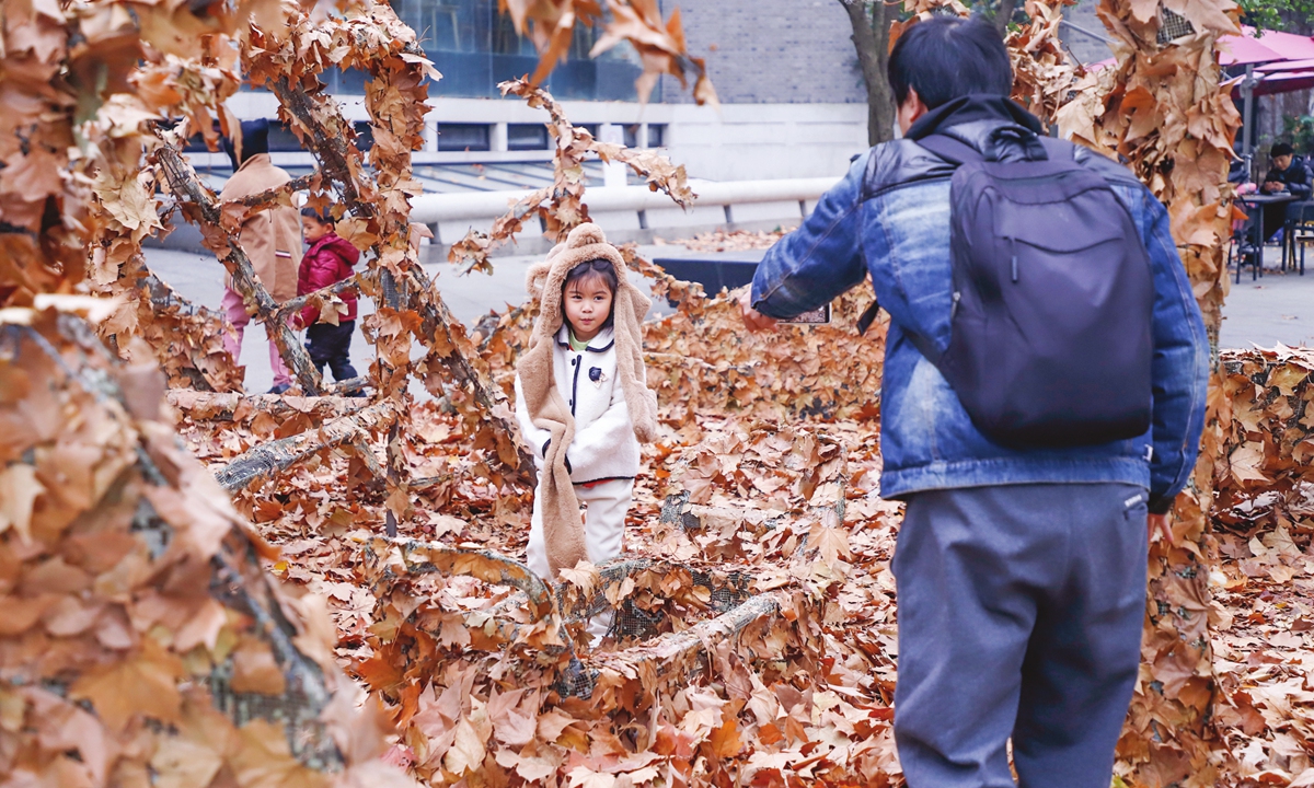 Parents take their children to watch autumn leaves sculptures at the 