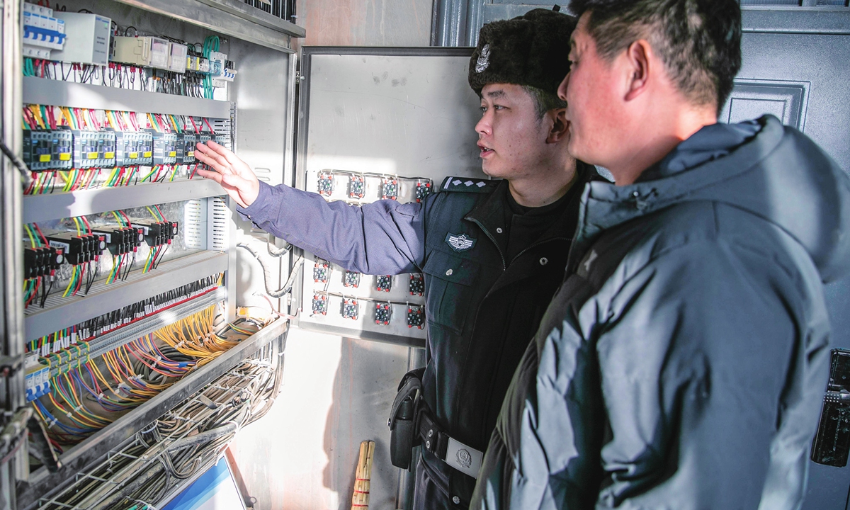A police officer (in uniform) inspects the operation of the power control system of a farm in Yili, Northwest China's 
Xinjiang Uygur Autonomous Region, on December 19, 2023. China was swept by cold waves over the past several days, and actions have been taken to ensure the normal lives of residents. Photo: VCG