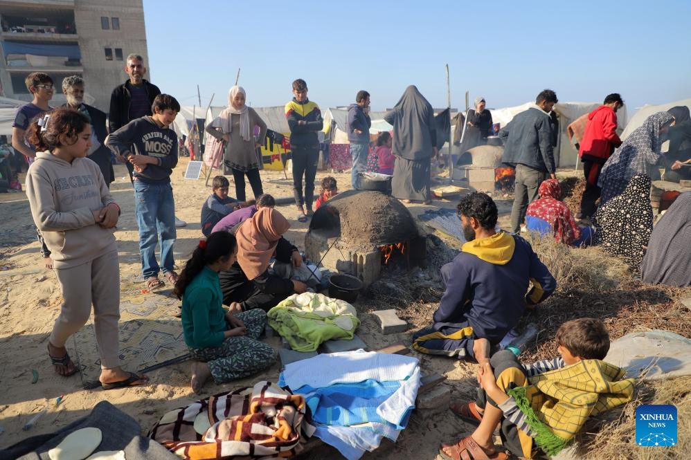 Displaced Palestinians prepare food at a temporary shelter in the southern Gaza Strip city of Rafah, on Dec. 18, 2023. UN officials and aid agencies have raised alarms about a humanitarian crisis in Gaza, including mass starvation and disease, as a vast majority of the region's 2.3 million people have been displaced during the ongoing two-month conflict.(Photo: Xinhua)