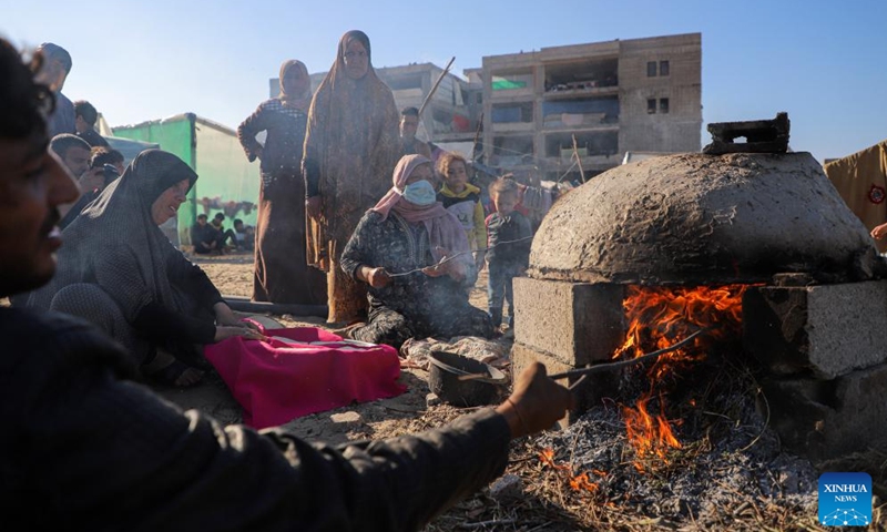 Displaced Palestinians prepare food at a temporary shelter in the southern Gaza Strip city of Rafah, on Dec. 18, 2023. UN officials and aid agencies have raised alarms about a humanitarian crisis in Gaza, including mass starvation and disease, as a vast majority of the region's 2.3 million people have been displaced during the ongoing two-month conflict.(Photo: Xinhua)