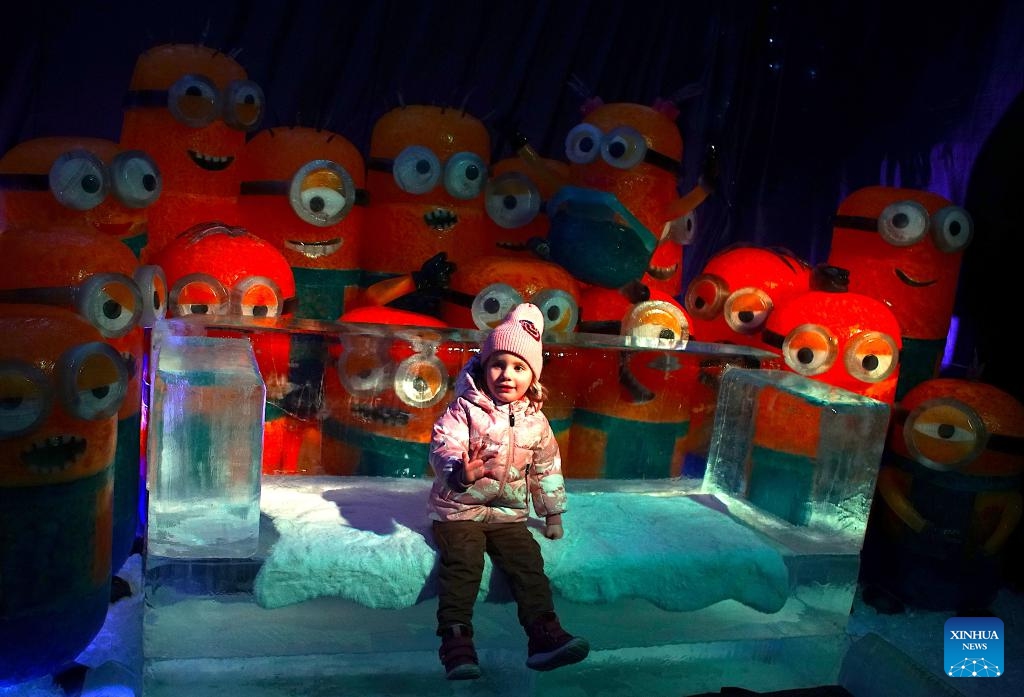 A girl sits on an ice bench at the Ice Magic exhibition in Prague, the Czech Republic, on Dec. 19, 2023. Ice Magic, an ice exhibition displaying various characters of fairy tales and cartoons, is held here from Dec. 11, 2023 to April 2024.（Photo: Xinhua)