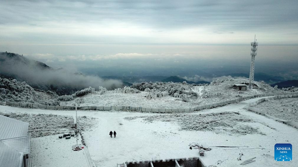 This aerial photo taken on Dec. 19, 2023 shows power supply technicians Yin Bin and Long Yujun heading to check the icing condition of the power transmission lines at an observation station on Xihuang Mountain on the border between Zhijiang Dong Autonomous County and Mayang Miao Autonomous County of Huaihua, central China's Hunan Province. Due to the recent strong cold wave sweeping across Hunan Province, some power transmission lines crossing Xihuang Mountain experienced icing（Photo: Xinhua)