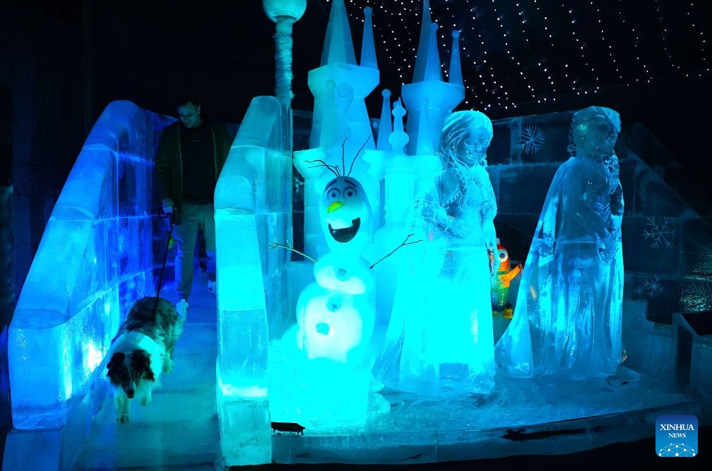 A man walks with a dog at an ice castle at the Ice Magic exhibition in Prague, the Czech Republic, on Dec. 19, 2023. Ice Magic, an ice exhibition displaying various characters of fairy tales and cartoons, is held here from Dec. 11, 2023 to April 2024（Photo: Xinhua)