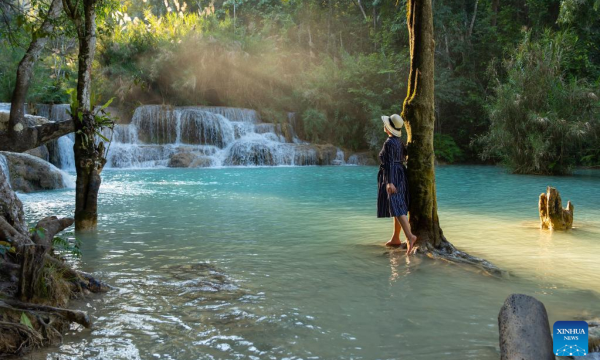 A visitor enjoys the view of Kuang Si waterfall in Luang Prabang, Laos, Dec 30, 2023. Photo:Xinhua