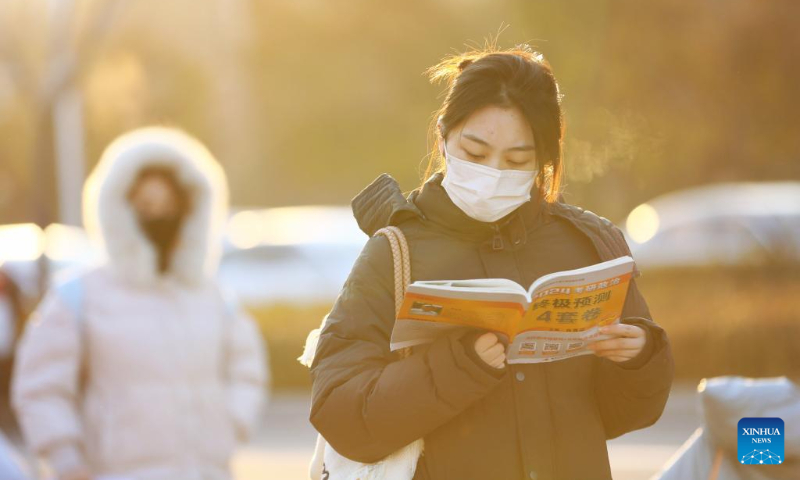 An examinee reviews her study materials before entering an examination site of the postgraduate admission exam in a primary school in Zaozhuang, east China's Shandong Province, Dec. 23, 2023. (Photo by Li Zhijun/Xinhua)