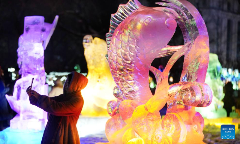 A visitor takes a selfie at the 50th Harbin ice lantern fair in Harbin, northeast China's Heilongjiang Province, Dec. 31, 2023. The ice lantern fair kicked off here on Sunday. (Xinhua/Wang Jianwei)