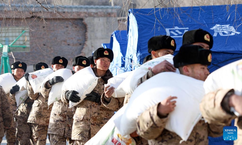 Members of the Chinese People's Armed Police Force help to carry bags of flour for quake-affected people in Liuji Township, Jishishan County, northwest China's Gansu Province, Dec. 21, 2023. The Chinese People's Liberation Army (PLA) and the People's Armed Police Force (PAPF) have deployed multiple rescue forces to quake-hit areas in response to a 6.2-magnitude earthquake that jolted northwest China's Gansu Province late Monday.(Photo: Xinhua)